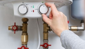 main sur un bouton d'un chauffe-eau 